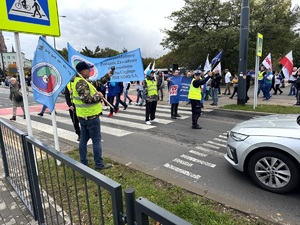 Umundurowani policjanci i oznakowane radiowozy oraz pracownicy przemysłu koksowniczego podczas zabezpieczenia manifestu.