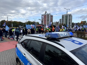 Umundurowani policjanci i oznakowane radiowozy oraz pracownicy przemysłu koksowniczego podczas zabezpieczenia manifestu.