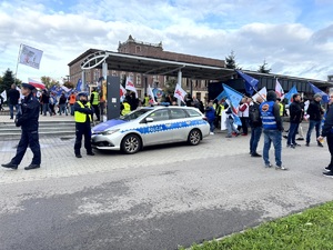 Umundurowani policjanci i oznakowane radiowozy oraz pracownicy przemysłu koksowniczego podczas zabezpieczenia manifestu.