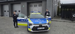 Widzimy policjantkę oraz policjanta stojących obok radiowozu.