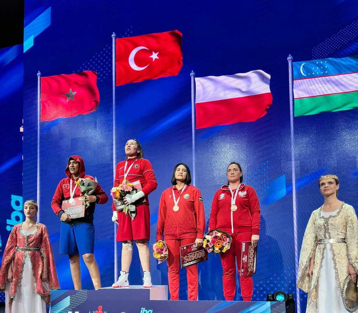 Podium na którym stoja finalistki Mistrzostw Świata w Boksie w Turcji. Na trzecim stopniu z brązowym medalem stoi policjantka Lidia Fidura.