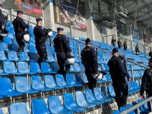 Policjanci z tarczami na stadionie piłkarskim.