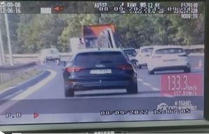 Widok ekranu wideorejestratora a na nim obraz drogowej trasy średnicowej po której pędzi samochód marki Audi.