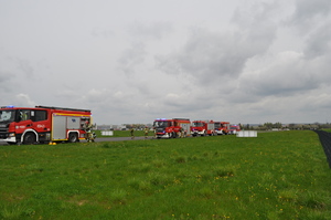 Na tle płyty lotniska aeroklubu gliwickiego w centralnym punkcie zdjęcia widać zaparkowane na płycie lotniska wozy bojowe Państwowej Straży Pożarnej w Gliwicach oraz Ochotniczej Straży Pożarnej z Bojkowa, łącznie 5 pojazdów. Przy pierwszym z lewej strony pojeździe widać dwóch strażaków wyciągających sprzęt ratowniczy, a przy kolejnym pojeździe widać czterech strażaków przygotowujących się do akcji pożarniczej.