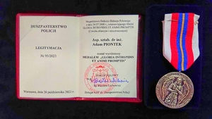 Na zdjęciu legitymacja medalu z nazwiskiem aspirant sztabowy doktor inżynier Adam Piontek oraz po prawej sam medal.