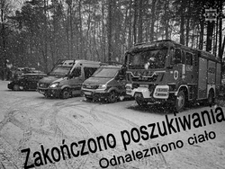 Na nocnym zdjęciu widzimy trójkę policjantów rozmawiajacych na tle pojazdów strażackich