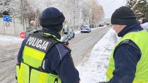 Na zdjęciu dwaj policjanci przy urządzeniu geodezyjny - teodolicie.