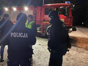 Na zdjęciu policjanci rozmawiający na leśnym parkingu.