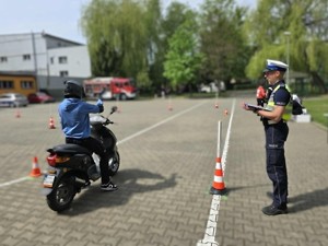 uczeń przed startem w konkurencji na motorowerze, obok stoi umundurowany policjant