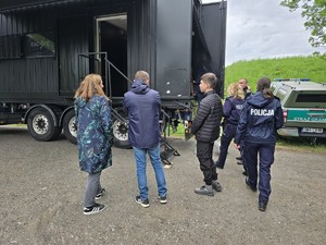 Cztery stojące osoby, w tle ciężarówka