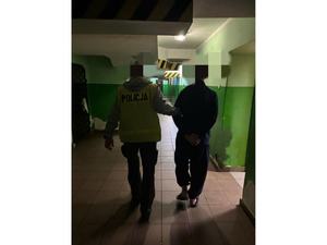 Policjant prowadzi korytarzem podejrzanego
