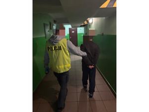 Policjant prowadzi korytarzem podejrzanego