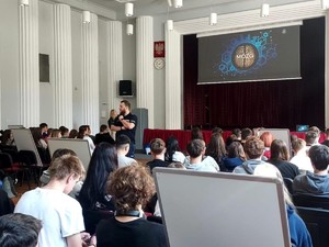 Na dużej sali siedzi grupa młodzieży podczas wykładów.