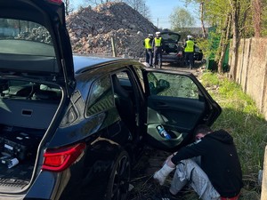 Samochód osobowy przy którym siedzi mężczyzna a w oddali stojący policjanci