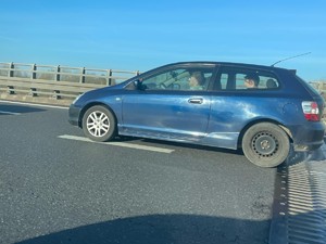 Pojazd jadący drogą, w środku znajduje się trzech mężczyzn