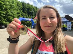 Na zdjęciu młoda kobieta trzymająca w ręku medal