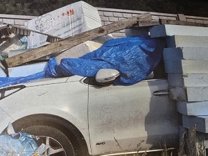 biały samochód przykryty niebieską plandeką i styropianem