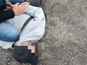 mężczyzna leżący na ziemi skuty kajdankami