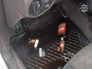 Zdjęcie przedstawia butelki po alkoholu leżące w samochodzie.