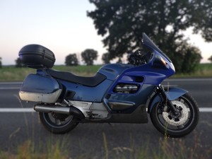 Na poboczu stoi granatowy motocykl.