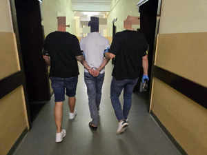 Dwóch policjantów prowadzi zatrzymanego korytarzem.