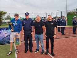 Na zdjęciu na boisku stoi Zastępca Komendanta Głównego Policji wraz z trzema nieumundurowanymi policjantami. W tle stoi orkiestra policyjna.