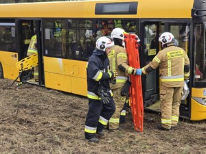 Strażacy prowadzą ewakuację poszkodowanych z autobusu.