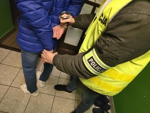 Na zdjęciu nieumundurowany policjanta zakłada kajdanki.