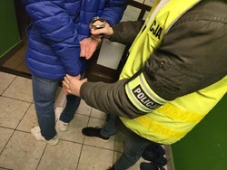 Na zdjęciu nieumundurowany policjanta zakłada kajdanki.
