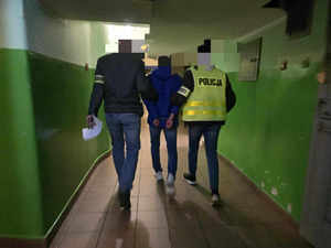 Zatrzymany wyprowadzany jest przez policjantów z pomieszczenia dla osób zatrzymanych