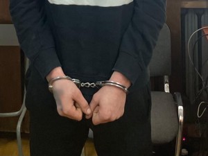 Ręce zatrzymanego mężczyzny w kajdankach.