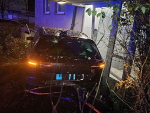 Rozbity samochód stoi przy klatce schodowej.