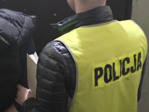 Policjant trzymający akta sprawy od tyłu