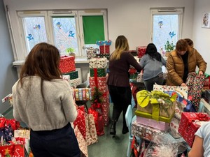 Pracownicy Ośrodka Pomocy Społecznej porządkują paczki w pomieszczeniu.