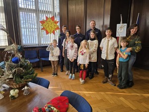 Na zdjęciu przedstawiciele Policji na czele z komendantem oraz dzieci kolędujące wraz z opiekunką.