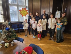 Na zdjęciu przedstawiciele Policji na czele z komendantem oraz dzieci kolędujące wraz z opiekunką.