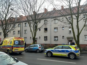 Na zdjęciu na ulicy stoi straż pożarna radiowóz Policji. W tle budynki mieszkalne.