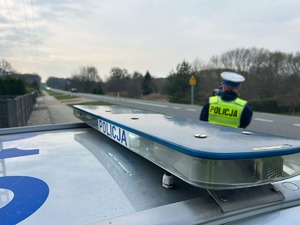 Policjant drogówki przy drodze oraz sygnały na dachu radiowozu