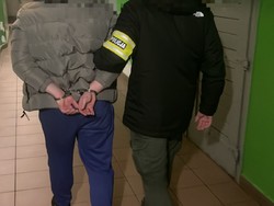 Policjant prowadzi korytarzem zatrzymanego