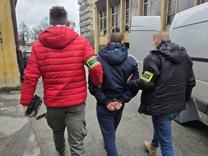 Policjanci na pwrkingu prowadza zatrzymanego do pojazdu