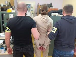 Na zdjęciu zatrzymany za oszustwa mężczyzna, którego trzymają pod ręce nieumundurowani policjanci