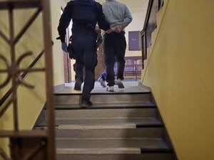 Umundurowany policjant prowadzi zatrzymanego