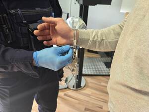 Policjant zdejmuje zatrzymanemu kajdanki przed daktyloskopią