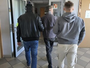 Policjanci nieumundurowani prowadzą zatrzymanego korytarzem