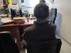 Na krześle widzimy zatrzymanego mężczyznę siedzącego tyłem podczas przesłuchania