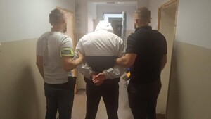 dwóch nieumundurowanych policjantów prowadzi zatrzymanego