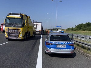 Na autostradzie stoi radiowóz oznakowany oraz pojazd ciężarowym. Miejsce wypadku drogowego.