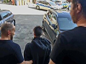 Dwóch nieumundurowanych policjantów prowadzi zatrzymanego