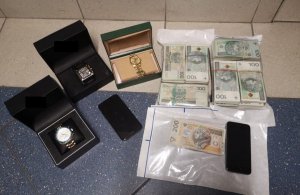 Zdjęcie kolorowe, przedstawiające zabezpieczone zegarki i pieniądze.