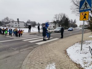 Zdjęcie przedstawiające przedszkolaków jak uczą się przechodzić przez przejście dla pieszych.